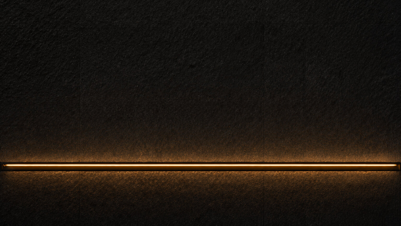 Architectural detail of warm amber light set into dark stone